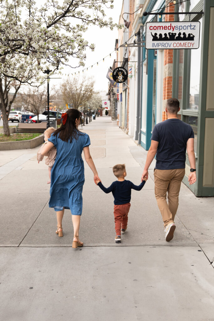 Family of four, holding hands, walking down city street for Salt Lake City Family Photos